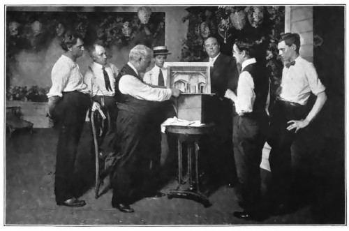 David Belasco designing a set with the Heads of His Artistic and Mechanical Departments, (photograph originally published in “The Theatre Through its Stage Door”, written by David Belasco, and published in 1919.)